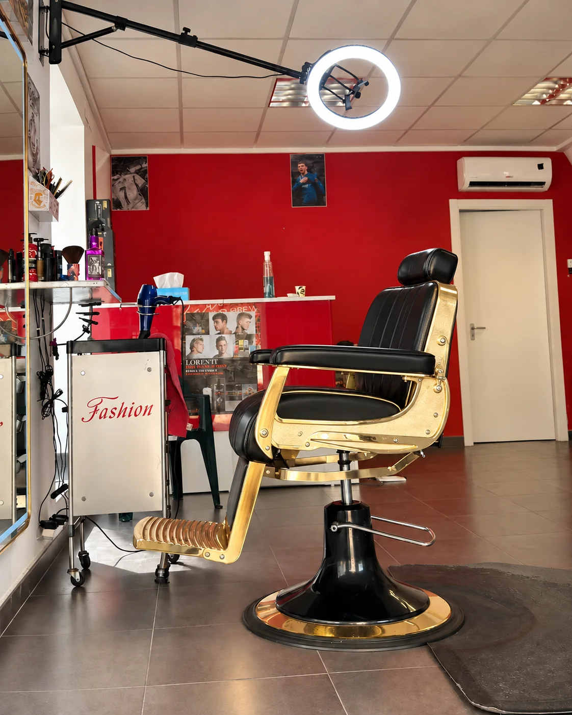 Interior de la barbería en Daimus, con sillón dorado y negro frente al espejo y paredes rojas